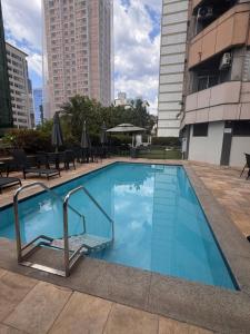 a blue swimming pool with chairs and buildings at Max Savassi Premier 14 in Belo Horizonte