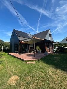 a black house with a deck in a yard at Grande maison en bois eco-responsable proche de la mer in Saint-Germain-sur-Ay