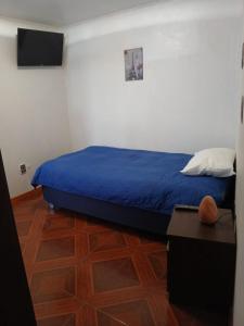 a bedroom with a bed with a blue blanket and a table at HabitacionIndependiente in El Cerrillo