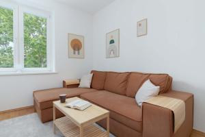 ein Wohnzimmer mit einem braunen Sofa und einem Tisch in der Unterkunft Atmospheric Apartment in a Green Area Pet-friendly by Noclegi Renters in Wzgórze Nowotki