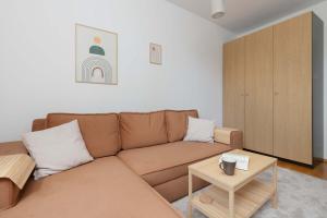 ein Wohnzimmer mit einem braunen Sofa und einem Tisch in der Unterkunft Atmospheric Apartment in a Green Area Pet-friendly by Noclegi Renters in Wzgórze Nowotki