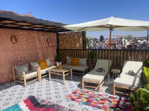 a patio with three chairs and a couch and an umbrella at Riad Dar Lamia in Marrakech
