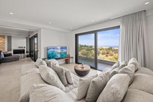 a large living room with a large couch and large windows at Serenity Blue Luxury Villa 7 Bedrooms in Koutouloufari