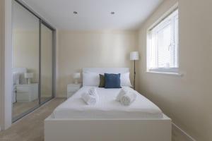 una camera da letto bianca con un grande letto bianco con asciugamani sopra di Eskdale House a Harwell