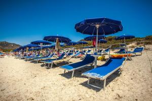 un mucchio di sedie e ombrelloni su una spiaggia di Hotel Fiore Di Maggio a Villasimius