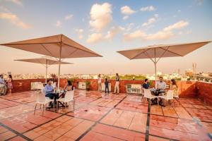 a group of people sitting at tables on a roof with umbrellas at FabHotel The Royal Suites - Nr Gopalan innovation mall in Bengaluru