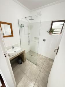 a white bathroom with a sink and a shower at Wazos Beach Villa in Durban
