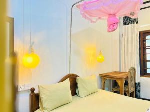 a room with a bed and a table and some lights at Nethu Freedom Cottage in Weligama