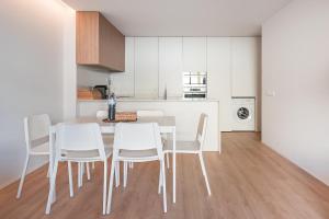 a white kitchen with a table and white chairs at GuestReady - Ultimate Retreat in Apúlia in Apúlia +40 photos