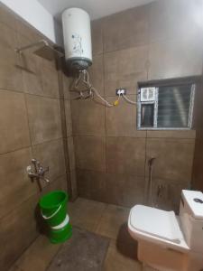 a bathroom with a toilet and a green bucket at SringeriRooms in Sringeri