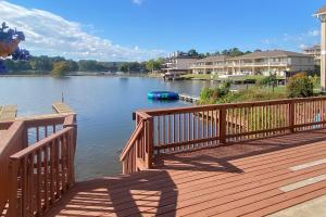 a wooden deck with a boat on the water at Central Terrace Retreat in Hot Springs