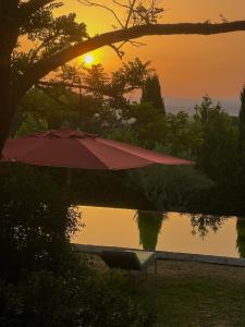 una sombrilla sentada junto a una piscina con puesta de sol en Villa Rossi Danielli - By TDF, en Viterbo