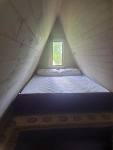 a bed in a small room with a window at Chale Cedrinho Sítio São Rafael in São José dos Pinhais
