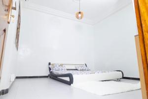 a bed in a room with a white wall at Appartement Meublée Confort et Élégance au Mariste in Dakar
