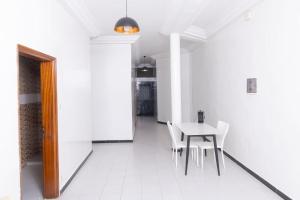 a white dining room with a table and chairs at Appartement Meublée Confort et Élégance au Mariste in Dakar +14 photos