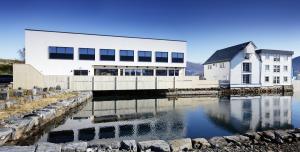 a white building next to a body of water at Rosenlund Hamn in Sande