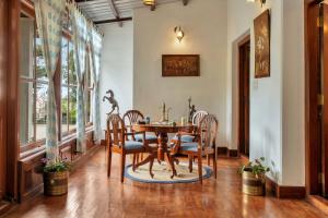 a dining room with a wooden table and chairs at SaffronStays Milton Abbott Estate, Ooty in Ooty