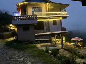 Cette maison dispose d'un balcon avec une table et un parasol. dans l'établissement The Hotel Orchid & Restaurant, à Kāskī