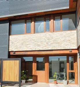 a house with large glass windows and a wooden door at Apart Sei - Rada Tilly - in Rada Tilly