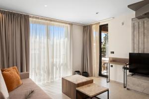 a living room with a couch and a television at Luxury Suites with BBQ next to Heraklion by Kalles Homes & Suites in Áno Kalésia