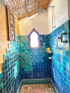 a bathroom with a blue tiled shower with a window at BaanBooLoo Village in Chiang Mai