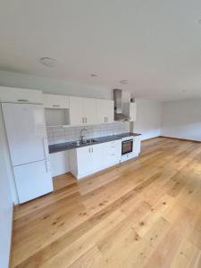 an empty kitchen with white cabinets and a wooden floor at Hallsberg Bostad in Hallsberg