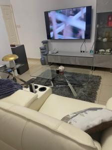 a living room with a white couch and a large tv at Jackson's View in Kwabenya