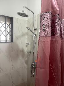 a shower with a red shower curtain in a bathroom at Jackson's View in Kwabenya +1 photo