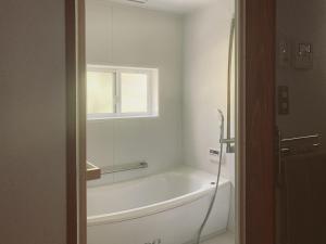 une baignoire blanche dans une salle de bains avec fenêtre dans l'établissement 森と温もりに包まれる長野飯綱高原の隠れ宿ヴァイオレットハウス, à Nagano 37 autres photos