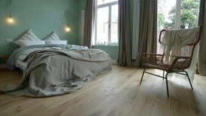 a bedroom with a bed and a chair and a window at The Doghouse B&B in Bruges