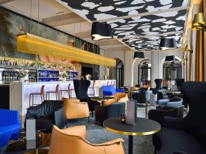 a restaurant with a bar with blue chairs and tables at Grand Hôtel La Cloche Dijon - MGallery Collection in Dijon