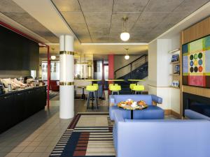 a restaurant with a blue couch and a table at Mercure Rennes Centre Parlement in Rennes