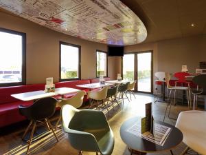 a restaurant with tables and chairs and a laptop on a table at ibis Hotel Brussels Airport in Diegem