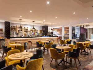 a restaurant with tables and chairs and a bar at Novotel Newcastle Airport in Newcastle upon Tyne