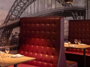 a restaurant with two tables and a red padded chair at Novotel Newcastle Airport in Newcastle upon Tyne