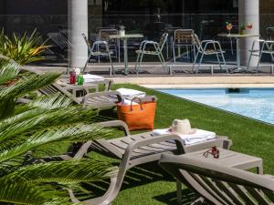 un grupo de sillas y mesas junto a una piscina en ibis Hyeres Centre, en Hyères