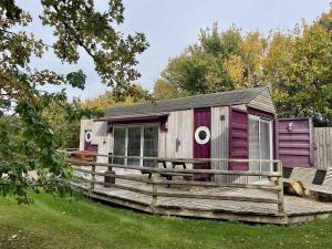 a small cabin with a deck in the grass at Purple CargoPod at Lee Wick Farm Cottages & Glamping in Clacton-on-Sea +6 photos