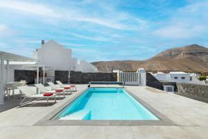 a swimming pool on a patio with white chairs at Villa Yaiza Secret 3 in Yaiza