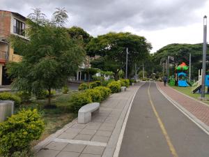 a sidewalk with benches and a playground in a park at Habitación King con baño privado, AC, cerca a centro de eventos, aeropuerto,zona bancaria y comercial in Yumbo