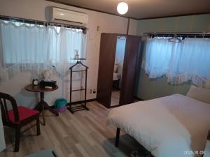 a bedroom with a bed and a chair and a table at Habitat Imazato Home Stay in Osaka