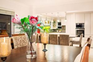 a dining room table with flowers in vases on it at Tenos On Calypso 12 in Langebaan