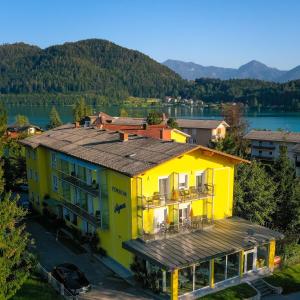 a yellow building in front of a lake at Pension Agnes in Sankt Kanzian