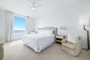 una camera da letto bianca con un letto e una sedia di Spanish Key Unit 301 a Perdido Key