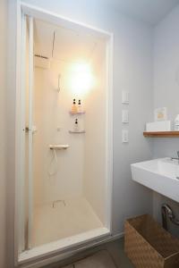 a shower with a glass door next to a sink at E10Hostel in Tokyo