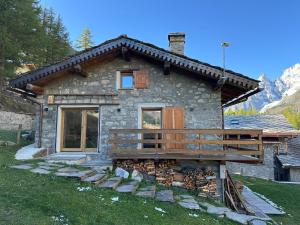 a small stone house with a deck in front of it at Baita Val Ferret CIR 0246 in Courmayeur