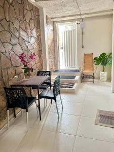 a dining room with a table and chairs and a stone wall at Oásis a 1km Parque COP30 in Belém
