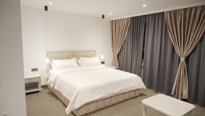 a bedroom with a large white bed and curtains at Qyzylorda Hotel in Kyzylorda