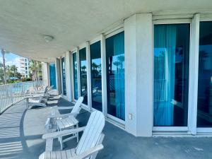 una fila di sedie a sdraio bianche su un portico di A Dose of Vitamin Sea a Destin Altre 46 foto