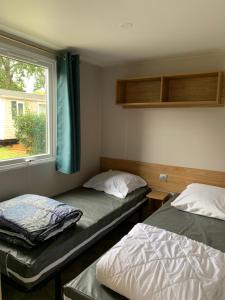 two beds in a room with a window at Mobil home 4 personnes in Pont-Aven