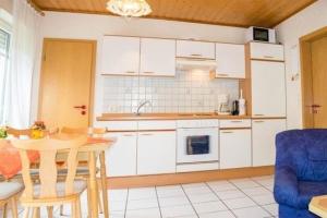 a kitchen with white cabinets and a table and a blue chair at Margret HA22 in Sögel
